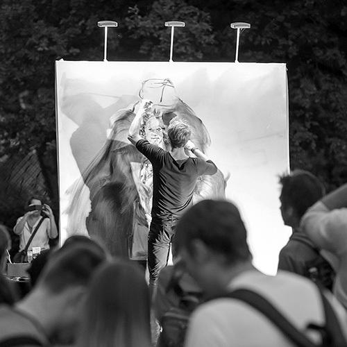 Livemalerei Marc Westermann Ein Mann steht vor einer riesigen Leinwand und malt. Davor sind viele Menschen, die zusehen