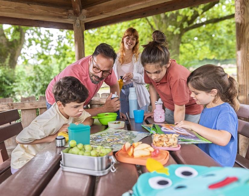 Eine Familie sitzt an einem Picnic-Tisch und studiert den Zoo-Plan