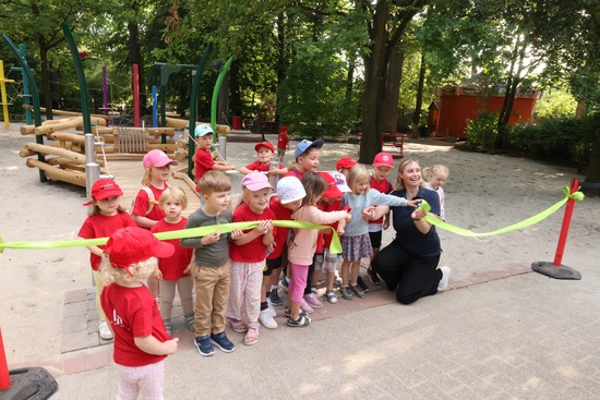 Eine Gruppe Kinder und Direktorin Schehka stehen vor einem gerade durchschnittenen Band