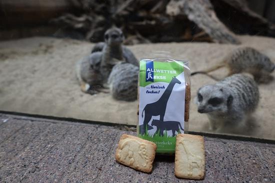 Eine Packung Kekse. 2 ausgepackte Butterkekse stehen vor der Packung. Im Hintergrund sieht man Erdmännchen