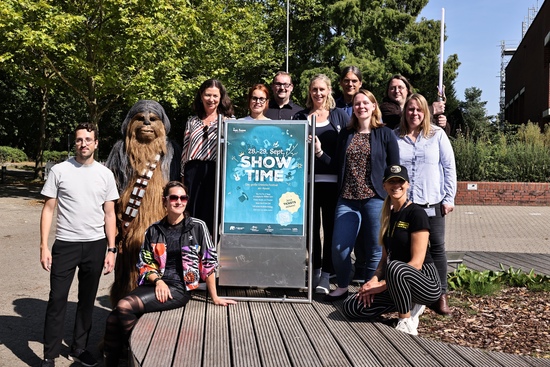 10 Menschen und 1 Wookie stehen vorm Plakat des Showtime Festivals