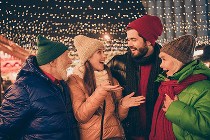 Eine Gruppe in Winterkleidung bei den XMAS Lights Münster mit Lichterketten im Hintergrund